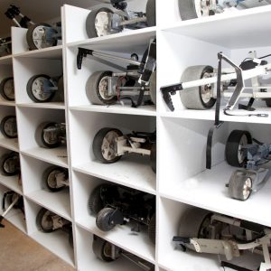 Multiple sets of golf cart wheels on white shelves.